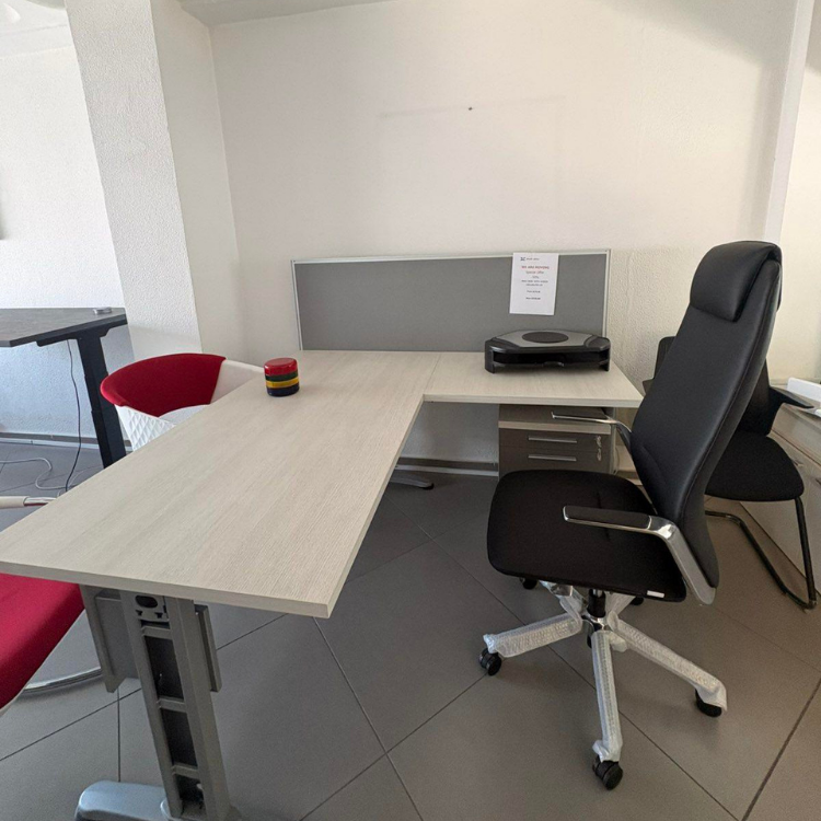 An office setting featuring a light-colored desk, a black ergonomic chair, and minimal office accessories.