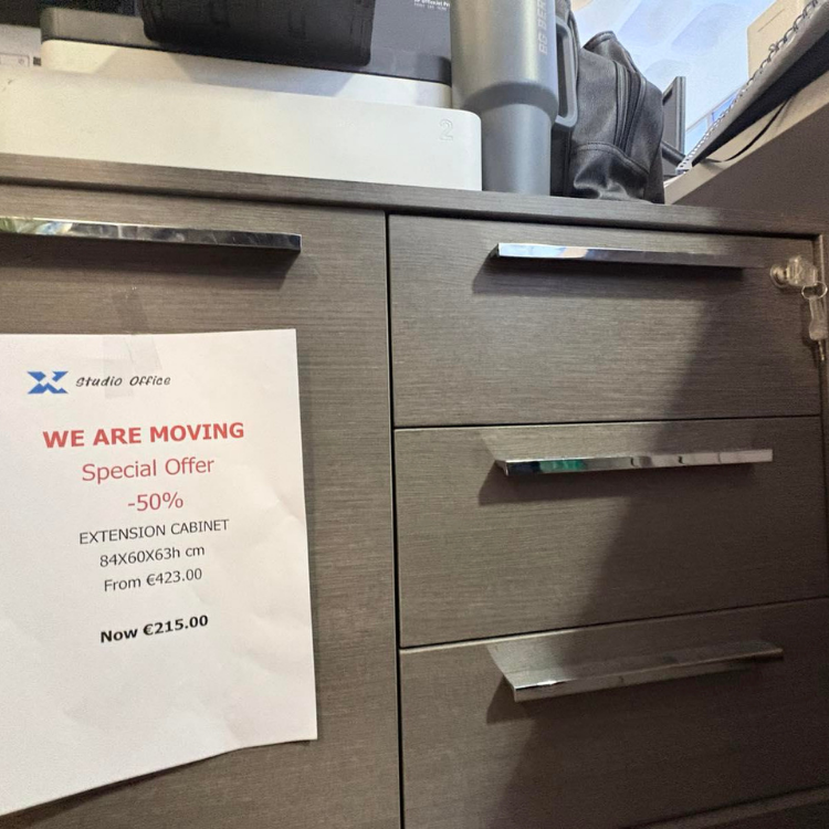 A gray wooden cabinet with chrome handles, featuring a promotional sign for an extension cabinet.