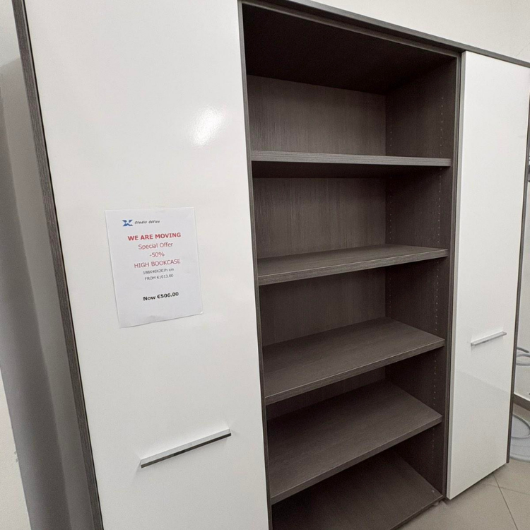 A tall bookcase with white doors and a grey wood-look interior features multiple shelves for storage and display.