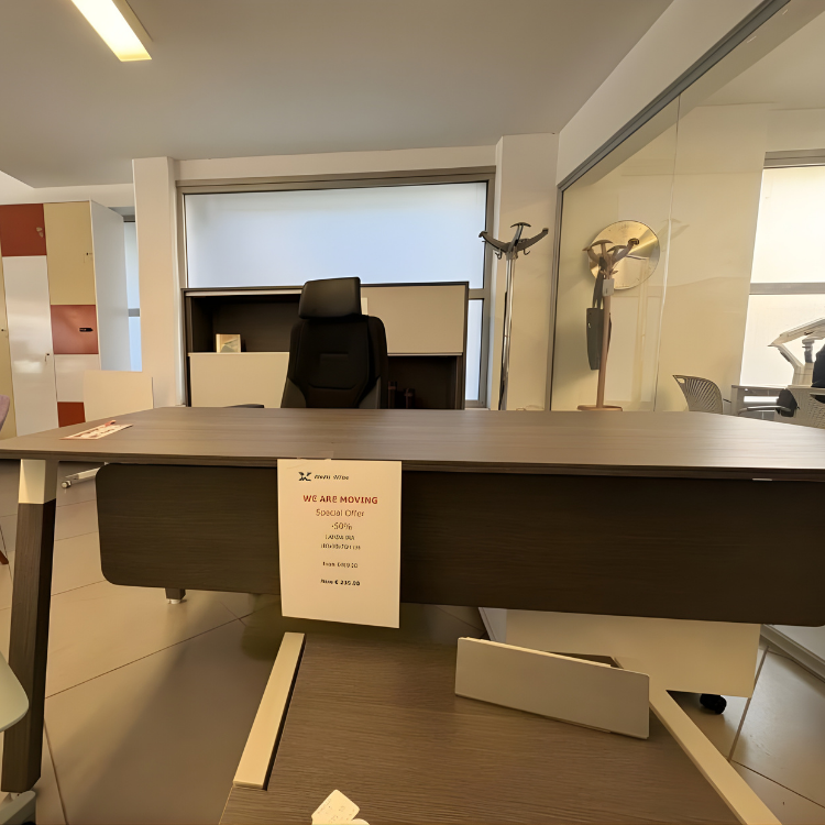 A modern office space features a dark brown desk with a black chair in the background, and a promotional sign.