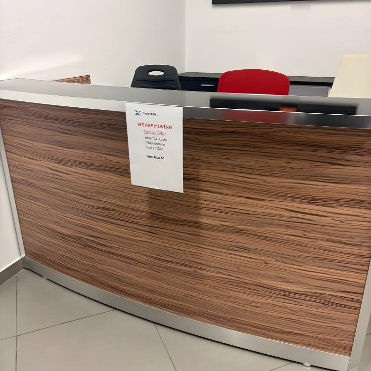A curved reception desk with a wood grain pattern and a sign attached to the front.